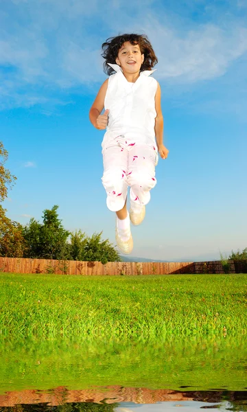 Lilla flickan hoppar mot vacker himmel — Stockfoto