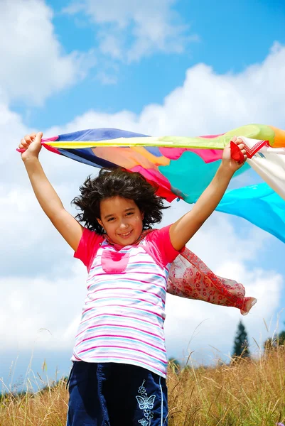 Uma menina bonito segurando cachecol no vento, ao ar livre — Fotografia de Stock