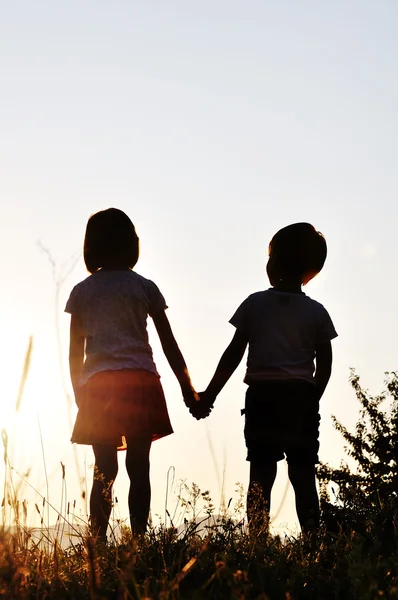 Zwei Kinder, männlich und weiblich, stehen gegen die Sonne, Sonnenuntergang, Romantik — Stockfoto