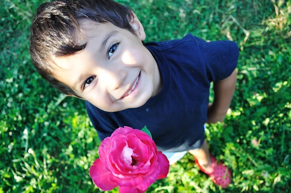 Happy beautiful child on ground with rose outdoor — Stock Photo, Image