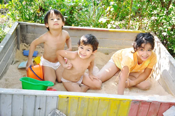 Crianças felizes brincando na caixa de areia — Fotografia de Stock