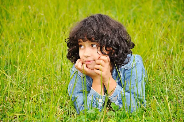 Una linda chica feliz tendida en tierra verde —  Fotos de Stock