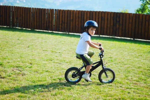 Atividade infantil com bicicleta no prado verde — Fotografia de Stock