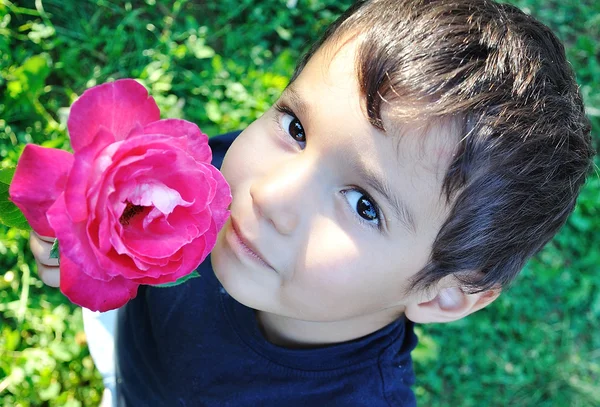 非常可爱的孩子与在他手中的粉色玫瑰 — 图库照片