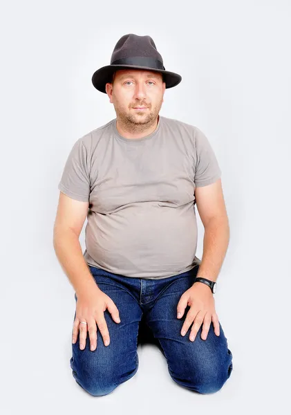 Joven macho sentado y sosteniendo un sombrero en la cabeza —  Fotos de Stock