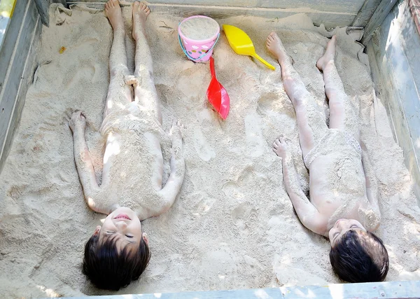 Dos niños varones jugando en la arena, escondiéndose y cubriéndose —  Fotos de Stock