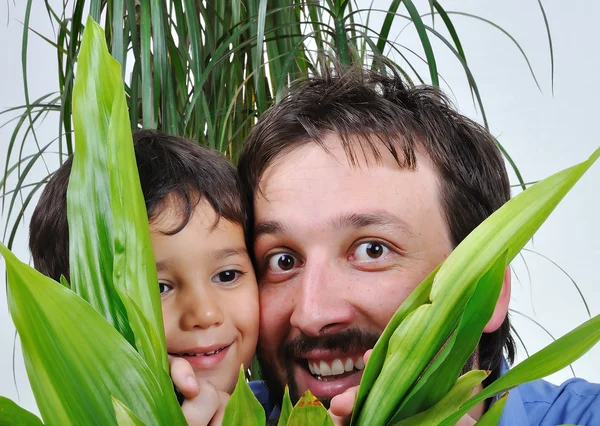 Szczęśliwy ojciec i syn, chowając się za zielony liść — Zdjęcie stockowe