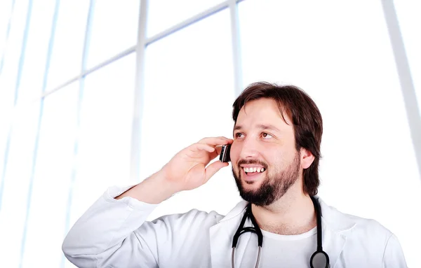 Jovem médico do sexo masculino falando por telefone dentro do prédio — Fotografia de Stock