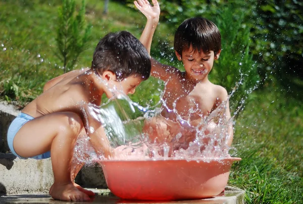 屋外の水と一緒に遊んで非常にかわいい子 — ストック写真