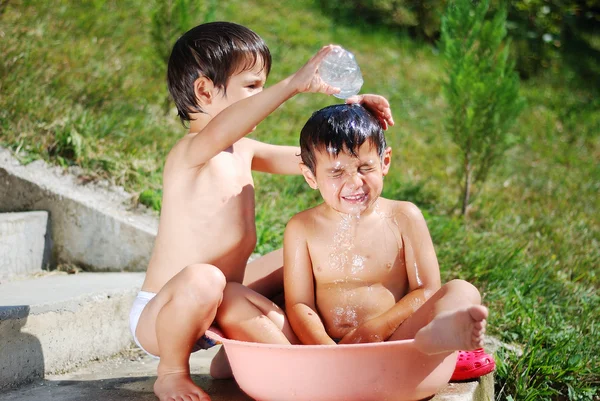 Mycket söta barn leker med vatten utomhus — Stockfoto