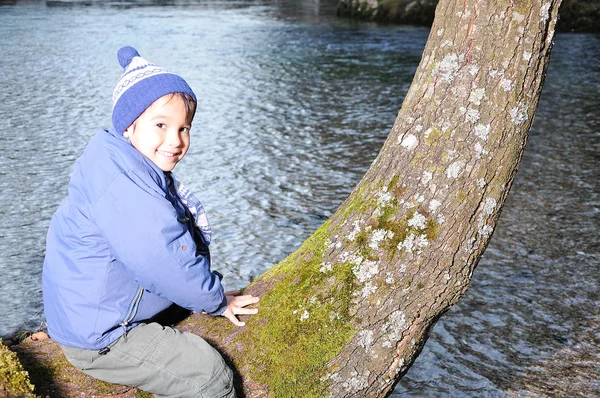 Kind auf Baum neben dem Fluss — Stockfoto