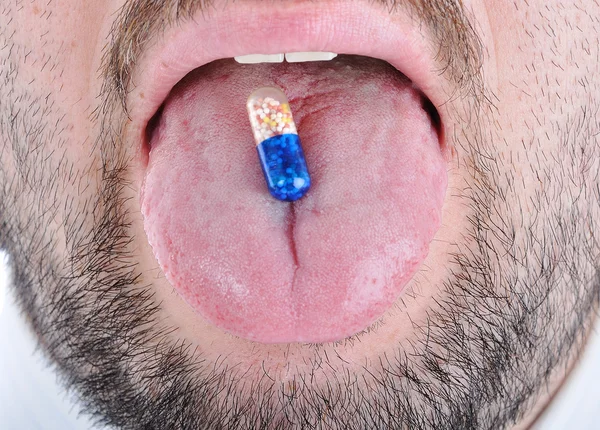 Drug pill on man's tongue — Stock Photo, Image
