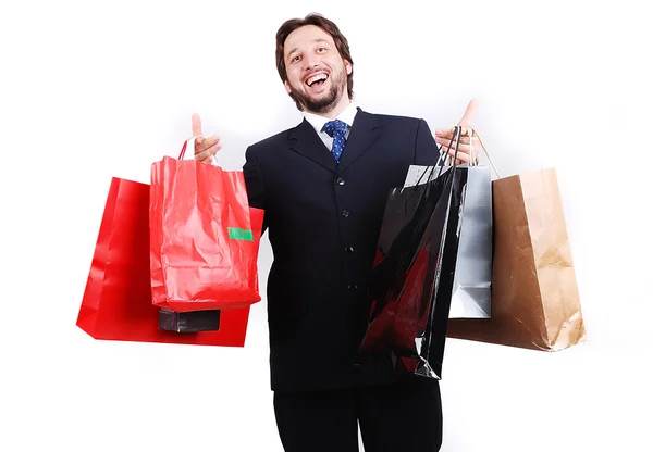 Joven atractivo hombre usando traje y sosteniendo bolsas de compras — Foto de Stock