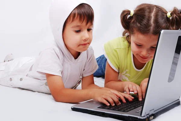 Мила пара дітей граються і навчаються на ноутбуці — стокове фото