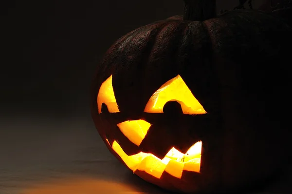 The carved face of pumpkin glowing on Halloween