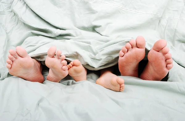 Ευτυχισμένη οικογενειακή στο κρεβάτι κάτω από το φύλλο — Φωτογραφία Αρχείου