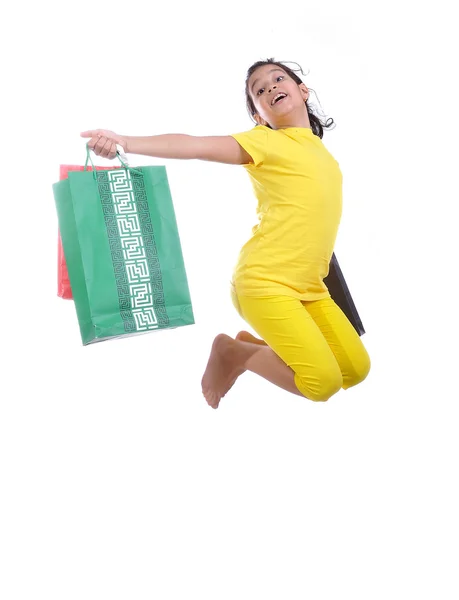 Pequena menina bonita em amarelo com bola amarela e sacos de compras — Fotografia de Stock