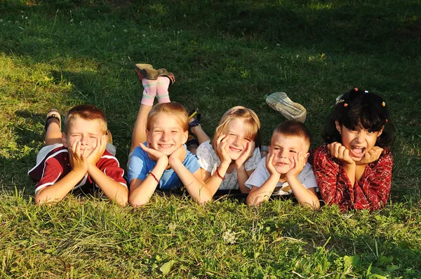 Щасливі красиві діти лежать на землі на відкритому повітрі Стокова Картинка
