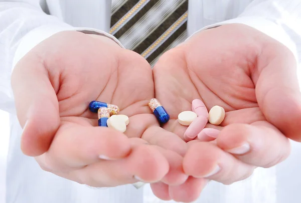Médico segurando pílulas na palma da mão Imagem De Stock
