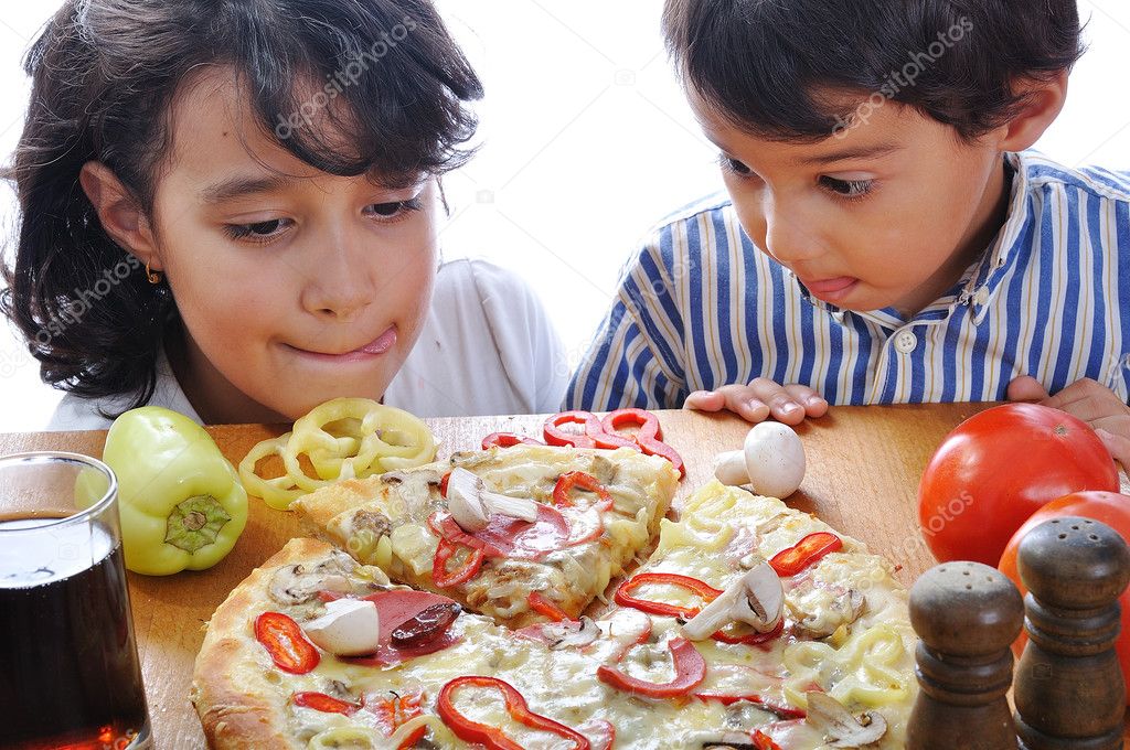 Two children with surprised face on pizza table