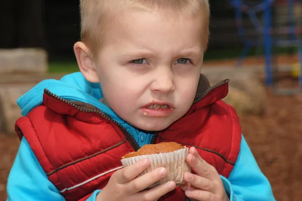 Szőke kisfiú enni muffin — Stock Fotó