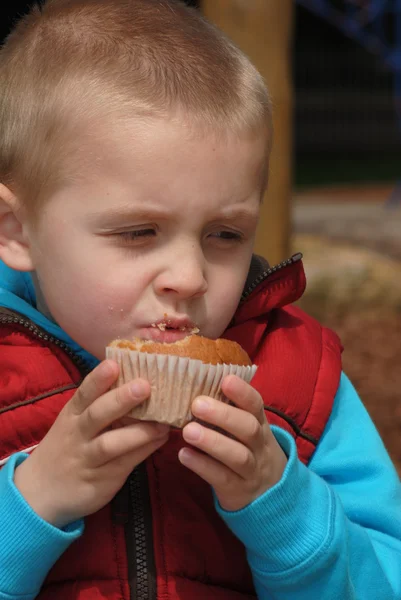 Блондин маленький мальчик ест кексы — стоковое фото