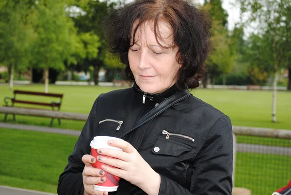 Starsza kobieta picia kawy w parku — Zdjęcie stockowe