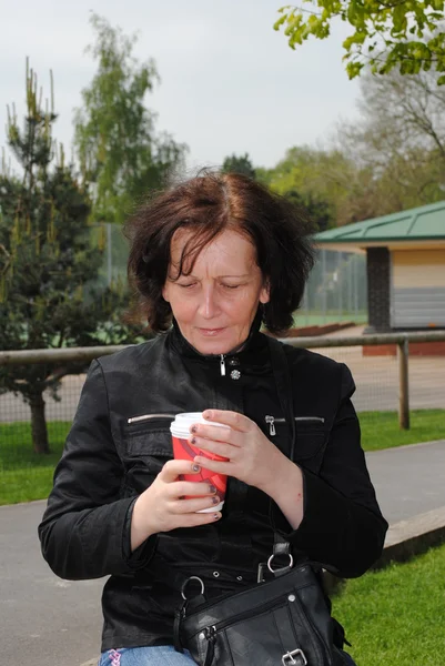 Ώριμη γυναίκα που πίνει καφέ στο πάρκο — Φωτογραφία Αρχείου