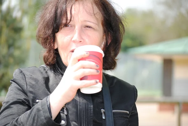 Volwassen vrouw koffie drinken in het park — Stockfoto