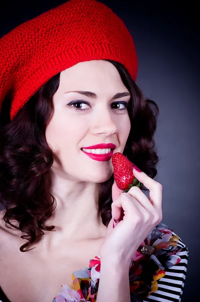 Mooi meisje in rode baret eten aardbei. — Stockfoto