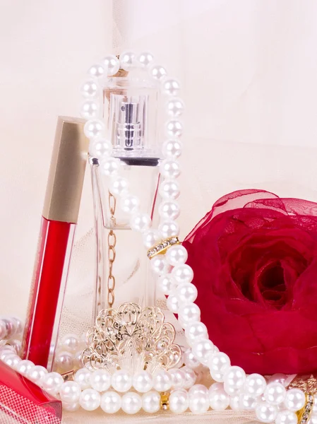 Frascos de perfume, lápiz labial rojo, plumas, rosas y perlas — Foto de Stock