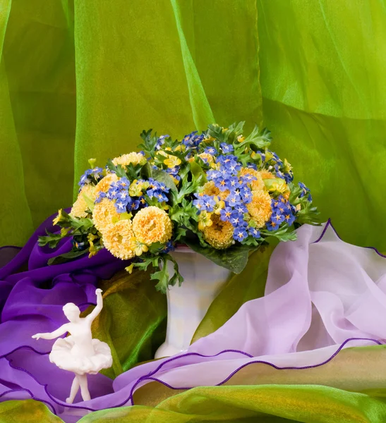 在一个玻璃花瓶和芭蕾舞演员在绿色背景上的美丽春天的花朵 — 图库照片