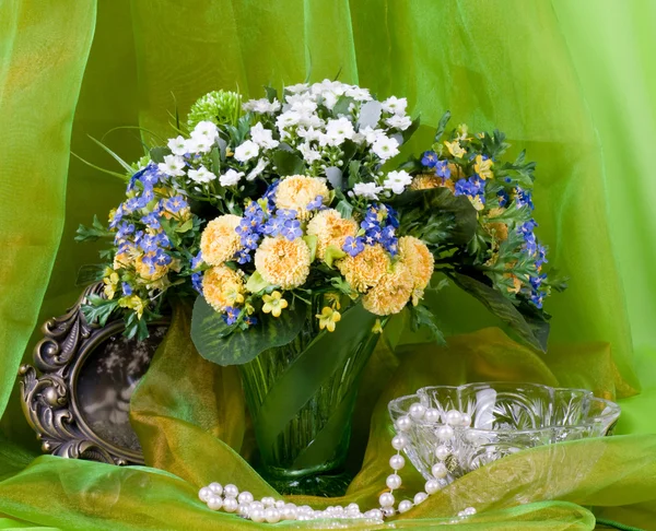 Bellissimi fiori primaverili in un vaso di vetro su sfondo verde — Foto Stock