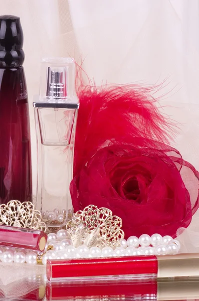 Парфюмерные бутылки, красная помада, перо, бусы из роз и жемчуга — стоковое фото