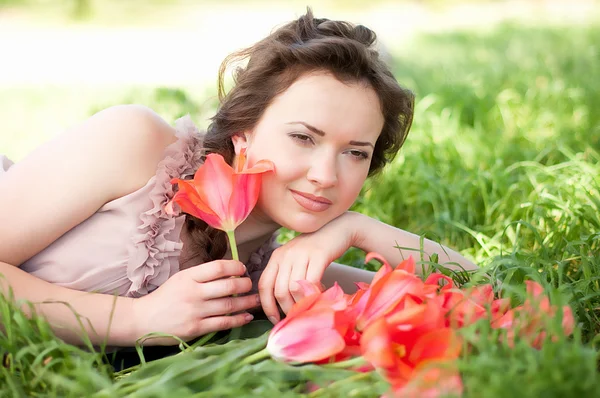 Piękna kobieta z tulipany czerwone wiosna w ogrodzie — Zdjęcie stockowe