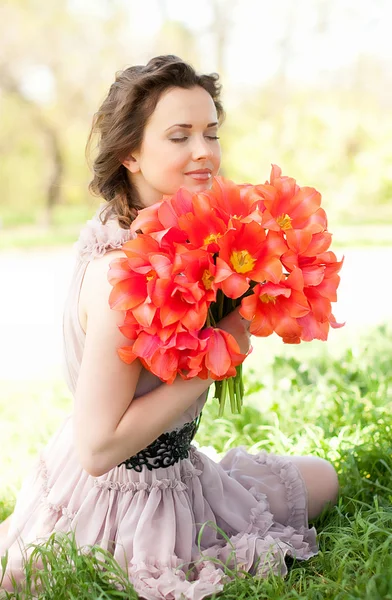 Piękna kobieta z tulipany czerwone wiosna w ogrodzie — Zdjęcie stockowe
