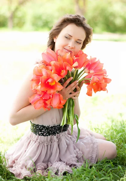 ผู้หญิงสวยกับทิวลิปฤดูใบไม้ผลิสีแดงในสวน — ภาพถ่ายสต็อก