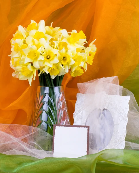 Prachtige Lentebloemen in een glasvaas en frame op achtergrond — Stockfoto