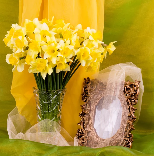 Hermosas flores de primavera en un jarrón de vidrio y marco en el fondo —  Fotos de Stock
