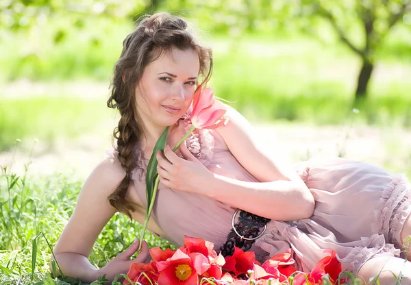 Mulher bonita com tulipas vermelhas da mola em um jardim — Fotografia de Stock
