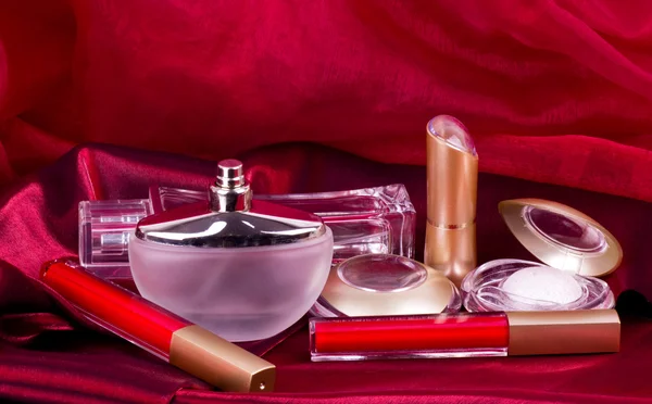 Parfumflesjes, rode lippenstift en oogschaduw — Stockfoto