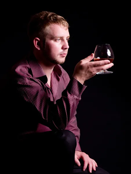 Jeune homme avec verre de brandy sur fond noir — Photo