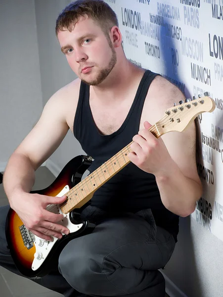 Jeune homme avec guitare sur fond sombre — Photo