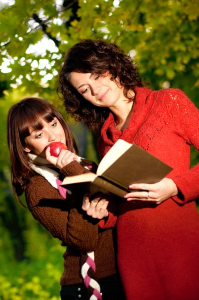 Beautiful smiling girls with book in park — Stock Photo, Image