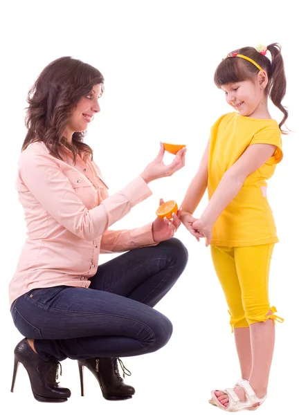 Beautiful little girl and her mother with orange — Stock Photo, Image