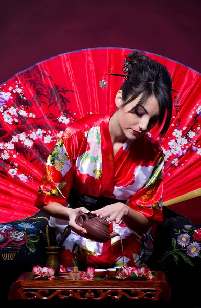 Woman in red Asian costume arranging Japanese tea ceremony — Stock Photo, Image