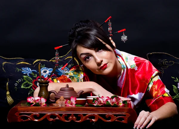 Женщина в красно-азиатском костюме устраивает японскую чайную церемонию — стоковое фото