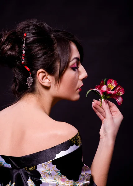 Женщина в азиатском костюме с красными цветами — стоковое фото