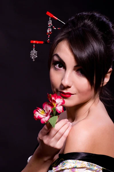 Женщина в азиатском костюме с красными цветами — стоковое фото