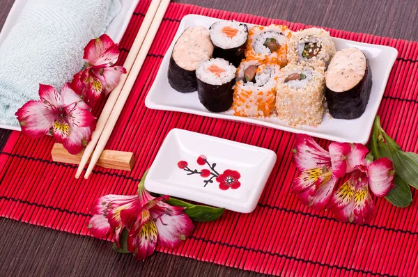 Set of sushi rolls on the white plate with flowers — Stock Photo, Image
